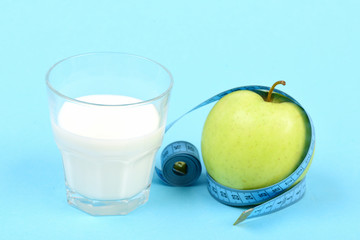 Glass of milk and apple wrapped around with measuring tape