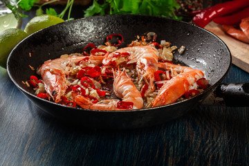 Shrimps roasted on frying pan with onion, garlic and chili