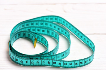 Circles made of cyan measuring tape on white wooden background