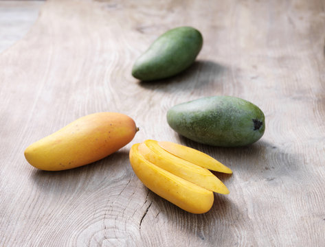 Mangoes sliced and whole on whitewashed wooden table