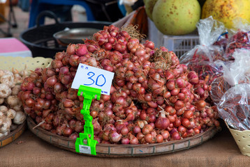 Close up Red onions in flat basket for sale with message price per kg.
