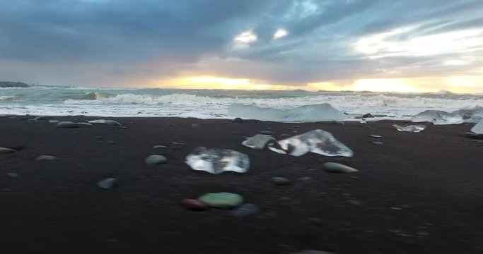 ICELAND – SEPTEMBER 2016 : Aerial shot of ice bergs and rocks on diamond beach at sunset