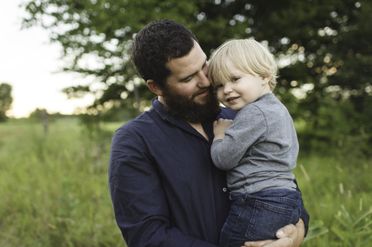 Father holding young son in field
