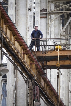 Worker on gantry in shipyard workshop