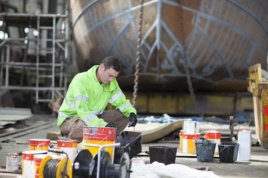 Worker mixing boat paints in shipyard