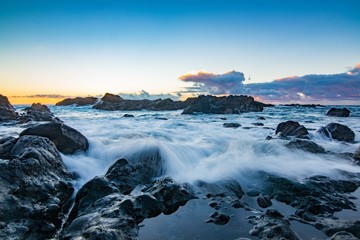 Rocky shore over the ocean during sunset.