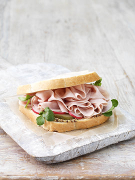 Wafer thin ham, wholegrain mustard, sliced gherkins and radish sandwich on sliced white bread