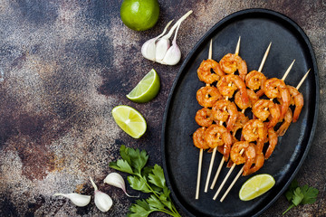 Grilled spicy lime shrimp skewers with creamy avocado garlic cilantro sauce. Top view, overhead,...