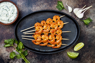 Grilled spicy lime shrimp skewers with creamy avocado garlic cilantro sauce. Top view, overhead, flat lay