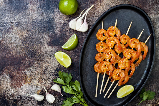 Grilled spicy lime shrimp skewers with creamy avocado garlic cilantro sauce. Top view, overhead, flat lay, copy space
