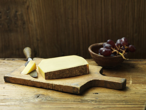 Arnaud comte cheese on cheese board with small wooden bowl of grapes