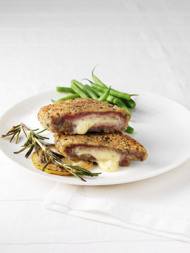 Plate of rose veal cordon bleu, slice of lemon, rosemary and green beans