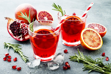 Red cocktail with blood orange and pomegranate. Refreshing summer drink on gray stone or concrete background. Holiday aperitif for Christmas party.
