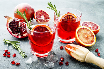 Red cocktail with blood orange and pomegranate. Refreshing summer drink on gray stone or concrete background. Holiday aperitif for Christmas party.