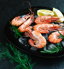 Tiger shrimps with lemon, rosemary on stone background.