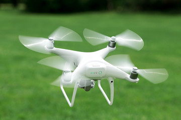 Closeup shot of a small drone flying above green lawn - 159603654