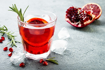 Red cocktail with blood orange and pomegranate. Refreshing summer drink on gray stone or concrete background. Holiday aperitif for Christmas party. Copy space