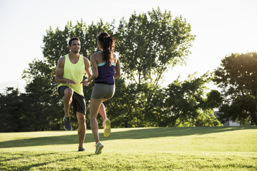 Young man and woman doing running on spot training in park