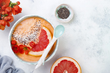 Healthy breakfast set. Superfoods smoothie bowl with chia seeds, coconut, grapefruit and quince flowers. Overhead, top view, flat lay, copy space.