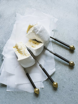 Overhead view of brie wedges separated with knives on greaseproof paper
