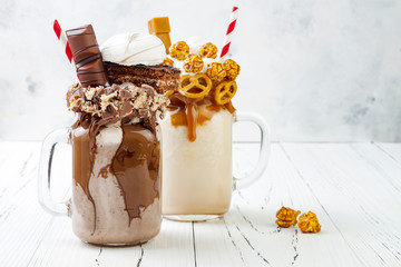 Caramel and chocolate indulgent exreme milkshakes with brezel waffles, popcorn, marshmallow, ice cream and whipped cream. Crazy freakshake food trend. - obrazy, fototapety, plakaty