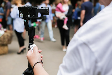 A mirrorless camera with a stabilized monopod and remote control. On the background of the fair in...