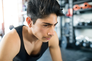 Young fit hispanic man in black sleeveless shirt in gym