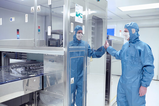 Male worker inspecting machinery in flexible electronics factory clean room
