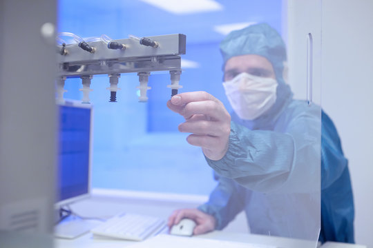 Male worker adjusting manufacturing machinery in flexible electronics factory clean room