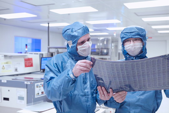 Male workers discussing flex circuit in flexible electronics factory
