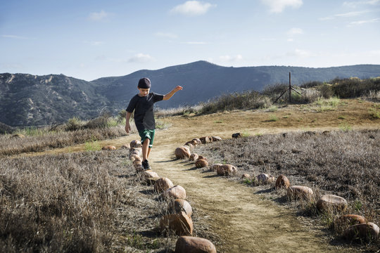 Boy stepping across row of footpath stones, Thousand Oaks, California USA