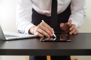 businessman working with mobile phone and stylus pen and laptop computer on wooden desk in modern office