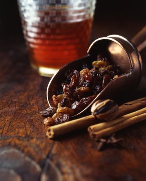Mixed raisins in scoop with cinnamon sticks and glass of real ale