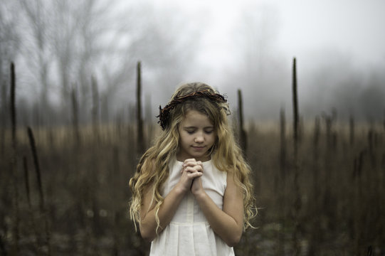 Portrait of long blond haired girl with head bowed in misty marsh