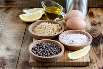 Mayonnaise ingredients on wooden background Salt Pepper Eggs Lemon Oil Rustic Ingredients for sauce Copy space