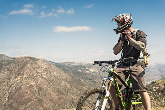 Downhill mountain biker putting on helmet