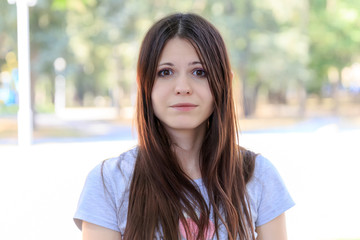 Fashion portrait of stylish girl with long black hair smiling and posing at camera. Woman Wearing in light blue top and shorts. Walking in park at summertime.