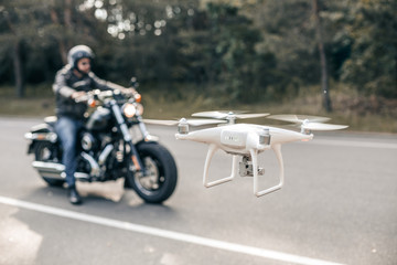 Fototapeta premium Motorbike on the road riding and hovering drone. Hovering drone taking pictures of biker.
