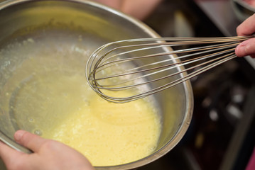 Close up female hand mixes ingredients with whisk