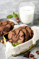 Chocolate cookies for breakfast with mint and hazelnut and a glass of milk on a gray table - 159611073