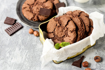 Chocolate cookies for breakfast with mint and hazelnut and a glass of milk on a gray table - 159611076