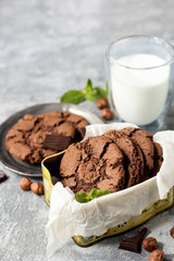 Chocolate cookies for breakfast with mint and hazelnut and a glass of milk on a gray table - 159611091