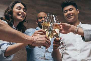 Happy young people clinking glasses of champagne during celebration