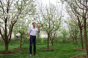 Adult man with megaphone between blooming trees in spring