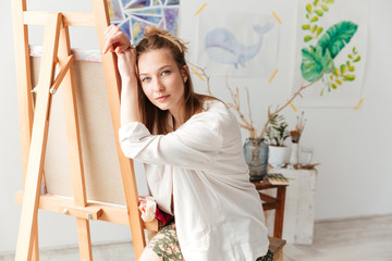 Attractive young caucasian lady painter at workspace