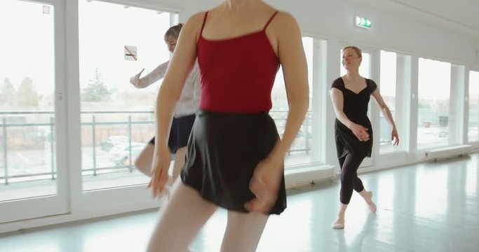Group of adult ballerinas standing with hands up in class for ballet performing a dance