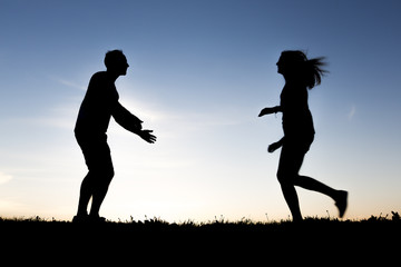 silhouette of romantic lovers with sunset on the back