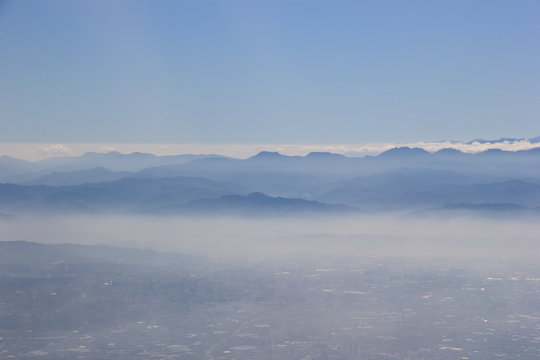 Fototapeta City and mountain in the fog, through from window airplane