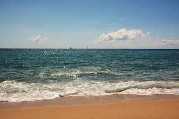 Fototapeta na wymiar Clean sandy beach, azure Mediterranean sea, sailboat on the horizon