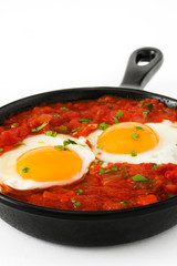 Mexican breakfast: Huevos rancheros in iron frying pan isolated on white background
